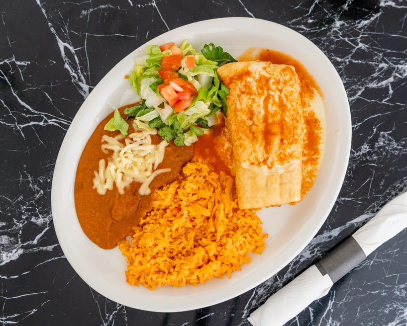 A Mexican combination plate with a burrito, refried beans, rice, and a side salad.